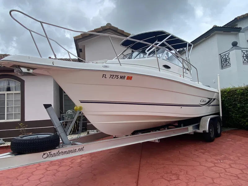 Slide: The Image of 2004 Cobia 250 Walk-Around boat on trailer, parked in residential driveway. - 12