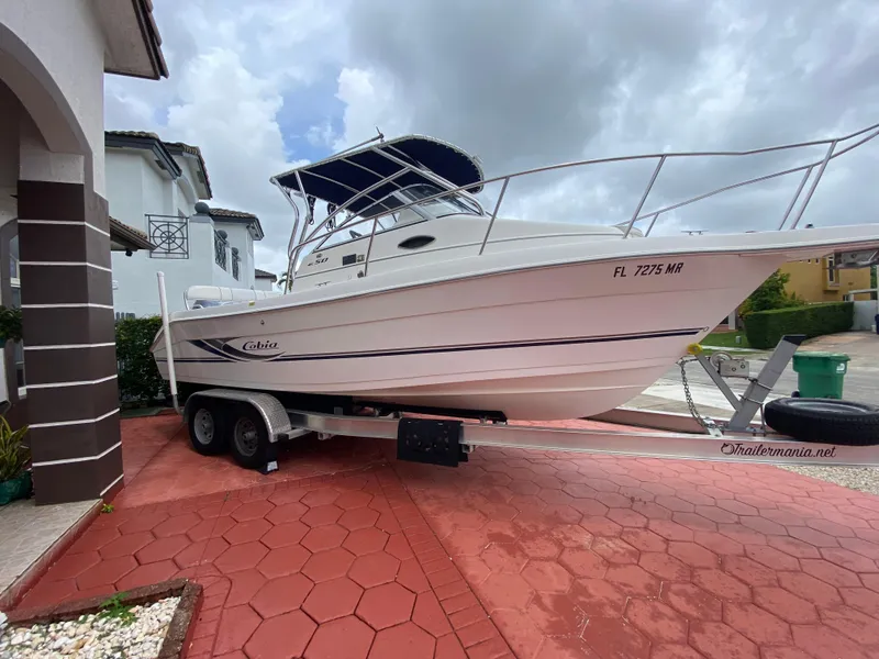 Slide: The Image of 2004 Cobia 250 Walk-Around boat on trailer, parked in residential driveway. - 13