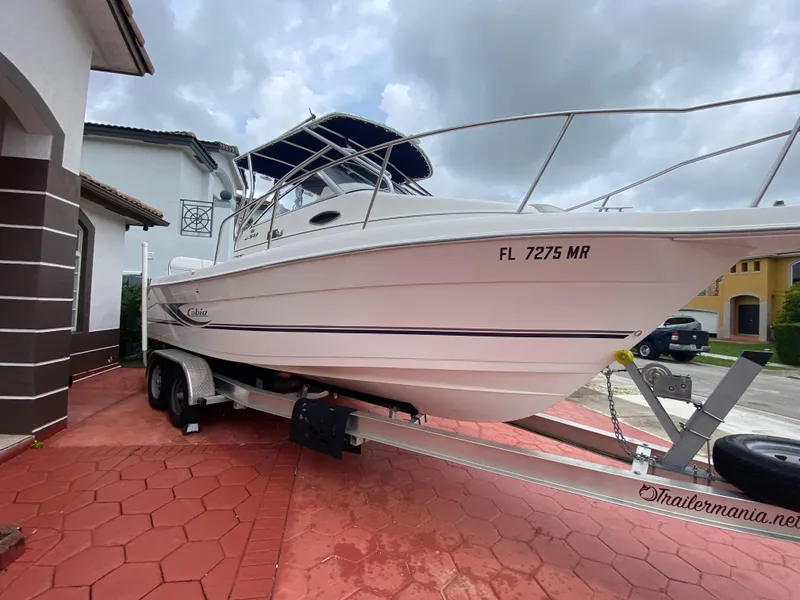 Slide: The Image of 2004 Cobia 250 Walk-Around boat on trailer, parked in residential driveway. - 14