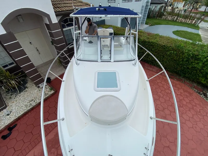 Slide: The Image of 2004 Cobia 250 Walk-Around boat parked on red brick driveway near house. - 15