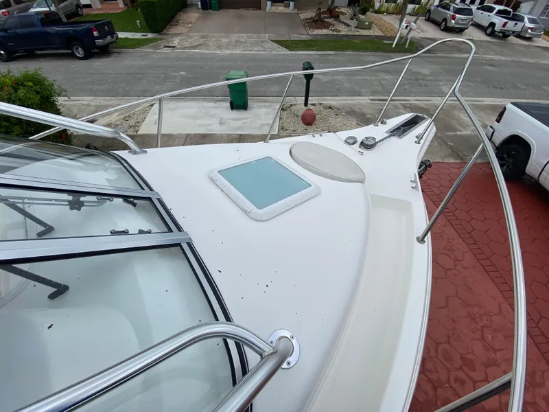 Slide: The Image of 2004 Cobia 250 Walk-Around boat deck with railing and hatch, parked in residential area. - 16