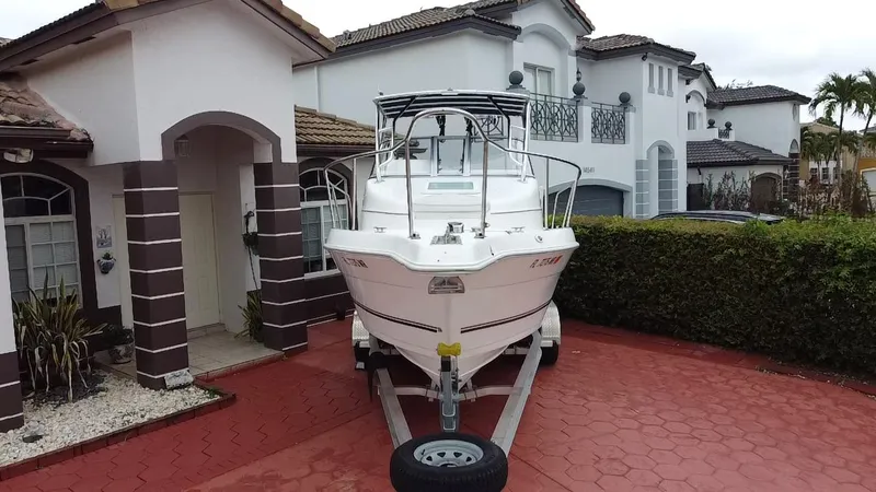 Slide: The Image of 2004 Cobia 250 Walk-Around boat on trailer in residential driveway. - 2