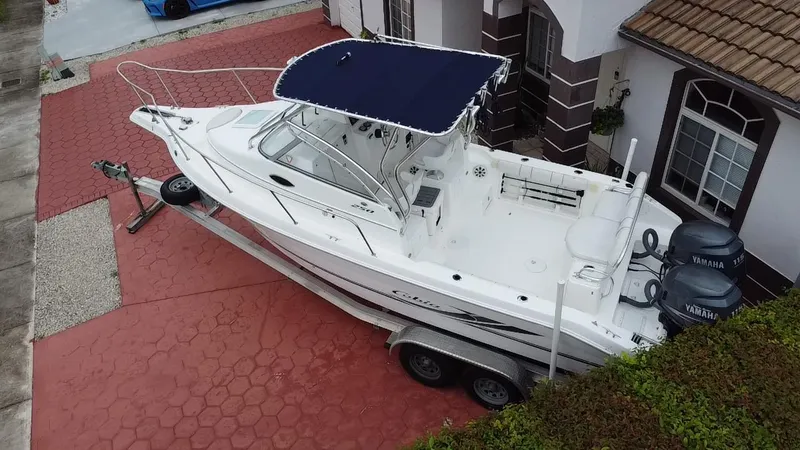 Slide: The Image of 2004 Cobia 250 Walk-Around boat on trailer, parked in residential driveway. - 20