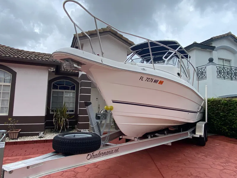 Slide: The Image of 2004 Cobia 250 Walk-Around boat on trailer, parked in residential driveway. - 22