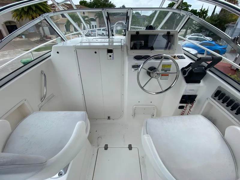 Slide: The Image of 2004 Cobia 250 Walk-Around boat cockpit with steering wheel and seating. - 25