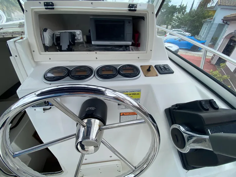 Slide: The Image of 2004 Cobia 250 Walk-Around boat dashboard with steering wheel and navigation instruments. - 27