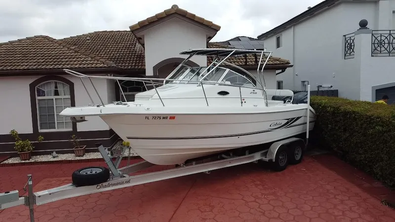 Slide: The Image of 2004 Cobia 250 Walk-Around boat on trailer in residential driveway. - 3