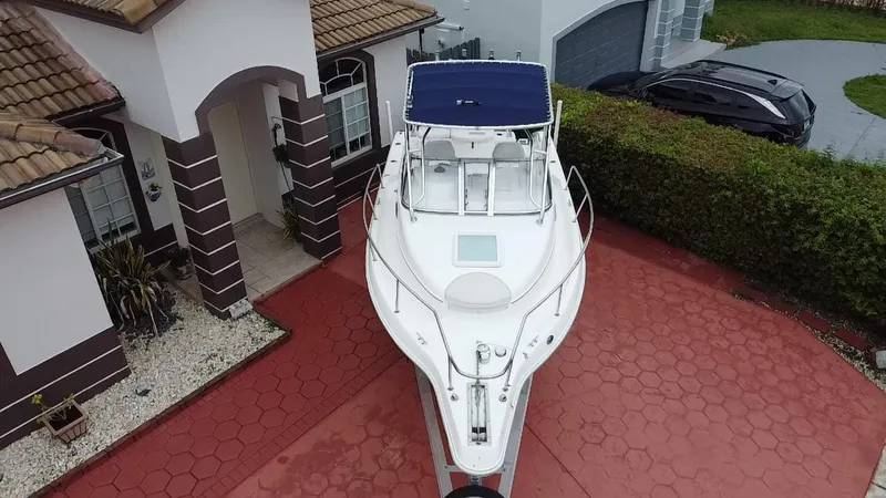 Slide: The Image of 2004 Cobia 250 Walk-Around boat parked on a red driveway beside a house. - 5