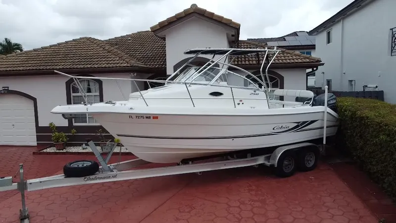 Slide: The Image of 2004 Cobia 250 Walk-Around boat on trailer, parked in front of a house. - 6