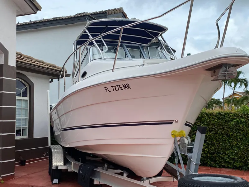 Slide: The Image of 2004 Cobia 250 Walk-Around boat on trailer, parked beside a house. - 7