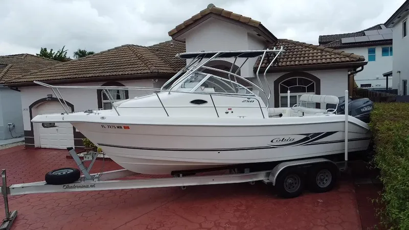 Slide: The Image of 2004 Cobia 250 Walk-Around boat on trailer in front of a house. - 9