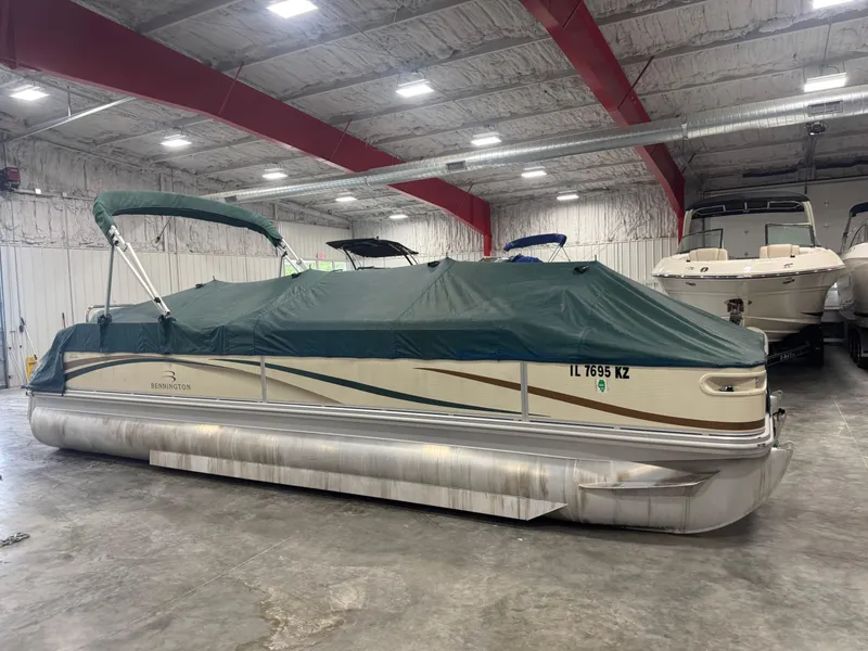 Slide: The Image of 2004 Bennington 2575 pontoon boat with green cover in indoor storage facility. - 12
