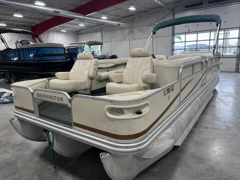 Slide: The Image of 2004 Bennington 2575 pontoon boat with beige seating, stored indoors. - 3