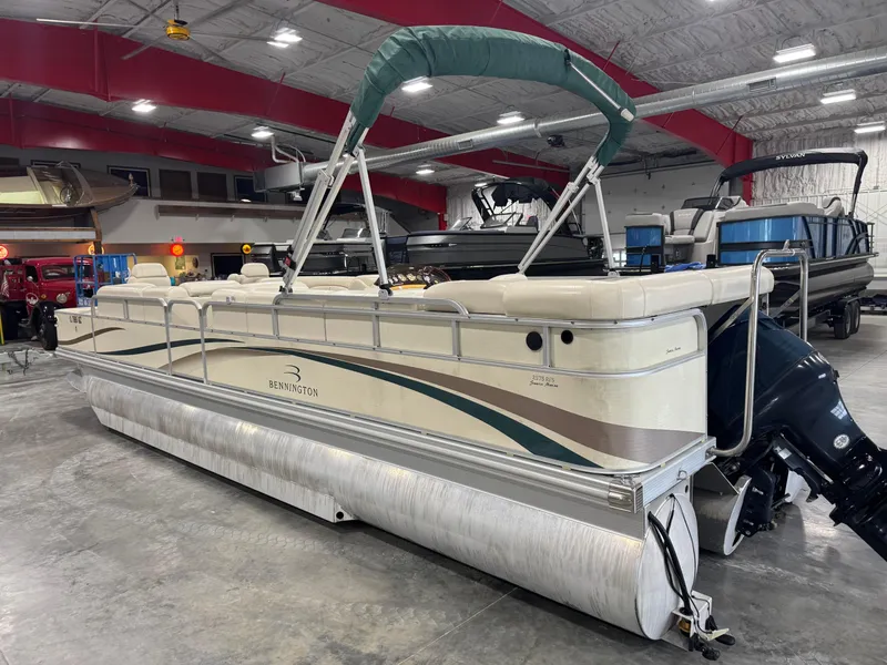 Slide: The Image of 2004 Bennington 2575 pontoon boat in indoor showroom, featuring beige seating and green canopy. - 5