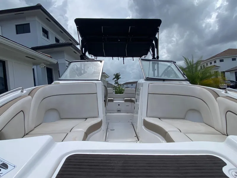 Slide: The Image of 2013 Yamaha Boats SX240 HO interior with seating, under cloudy sky, near modern homes. - 13