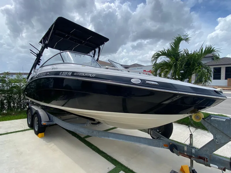 Slide: The Image of 2013 Yamaha Boats SX240 HO on trailer, parked outdoors under cloudy sky. - 14