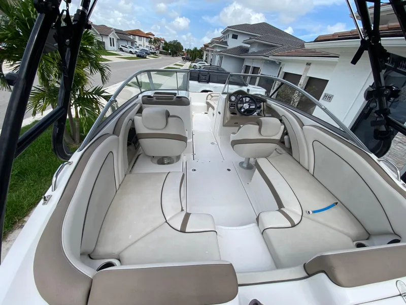 Slide: The Image of 2013 Yamaha Boats SX240 HO interior with beige seating and steering wheel, parked in residential area. - 16
