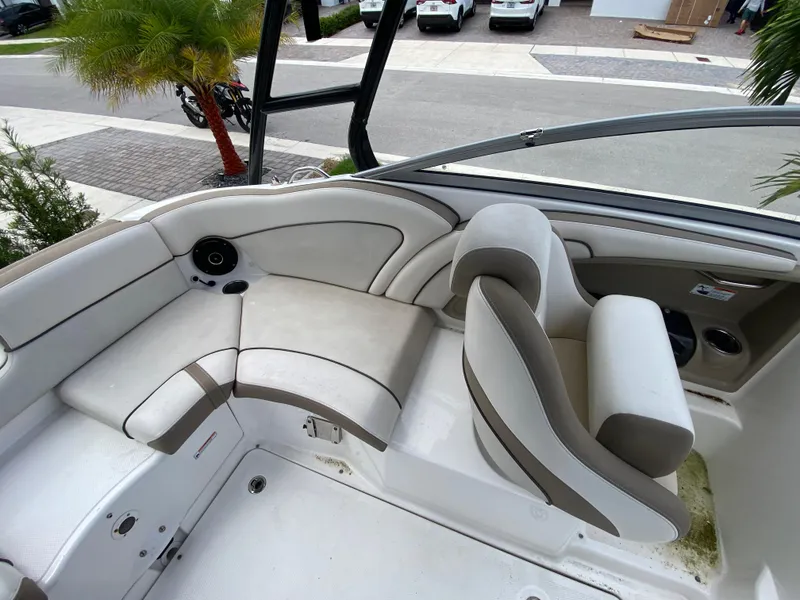 Slide: The Image of 2013 Yamaha Boats SX240 HO interior with beige seating and speaker, parked near palm trees. - 18