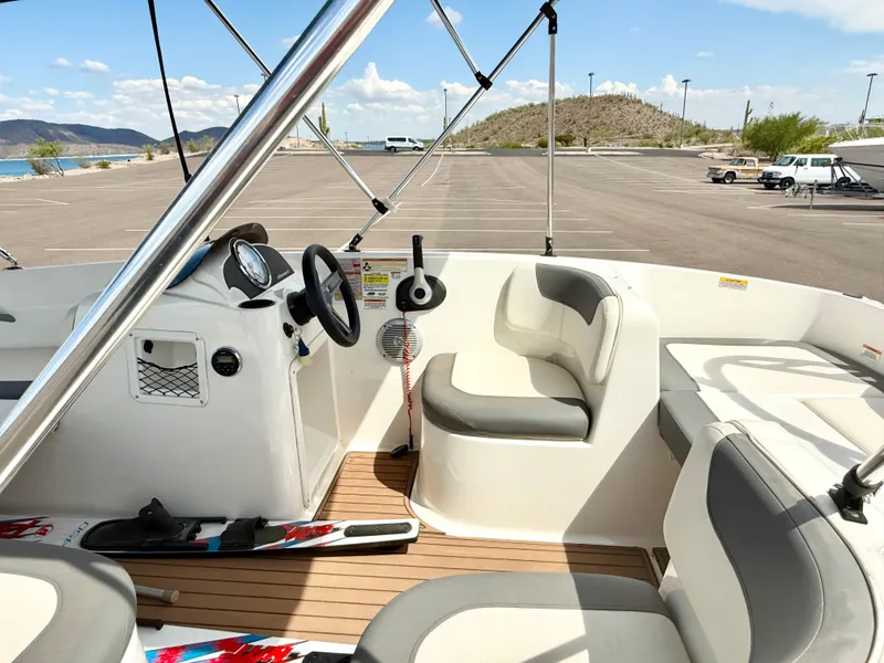 Slide: The Image of 2017 Bayliner Element E16 boat interior with seating and dashboard, parked near a scenic lake. - 9