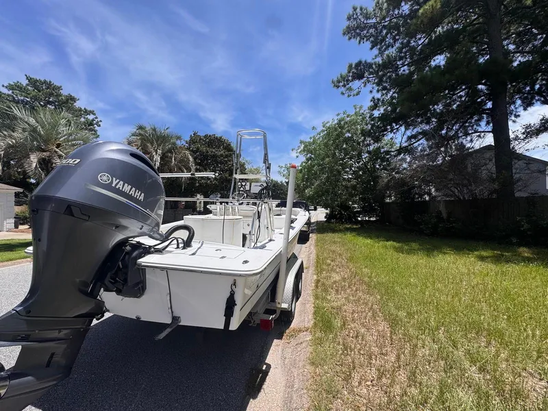 Slide: The Image of 2018 Intruder 23 SKIFF boat with Yamaha engine on a trailer, parked near trees. - 2