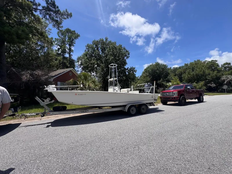 Slide: The Image of 2018 Intruder 23 SKIFF boat on trailer, parked beside a red truck on a sunny day. - 5