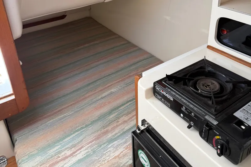 Slide: The Image of Interior of a 1994 Albin 28 Tournament Express with a compact stove and sleeping area. - 10