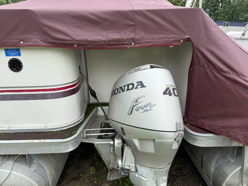 Slide: The Image of 1998 Sweetwater 24RE pontoon boat with Honda 40 outboard motor, covered in maroon tarp. - 2