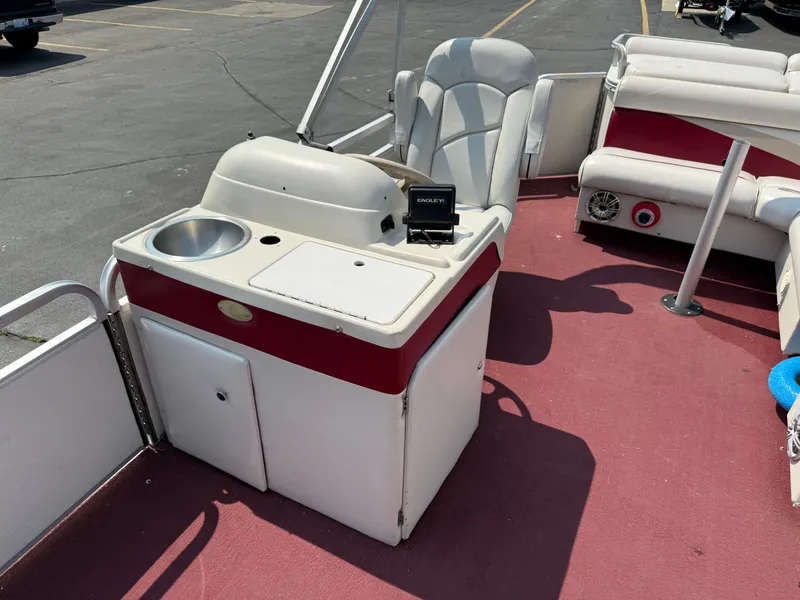Slide: The Image of 1998 Sweetwater 24RE boat interior with seating and a small sink on red carpet. - 5