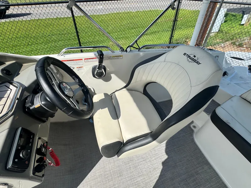 Slide: The Image of 2021 Stingray 212 SC boat interior with steering wheel and cushioned seat. - 15