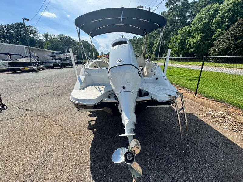 Slide: The Image of 2021 Stingray 212 SC boat with canopy, rear view, parked outdoors. - 2