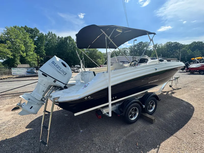 Slide: The Image of 2021 Stingray 212 SC boat with Suzuki outboard motor on trailer, parked outdoors. - 3