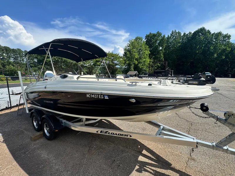 Slide: The Image of 2021 Stingray 212 SC boat on trailer with canopy, parked outdoors. - 4
