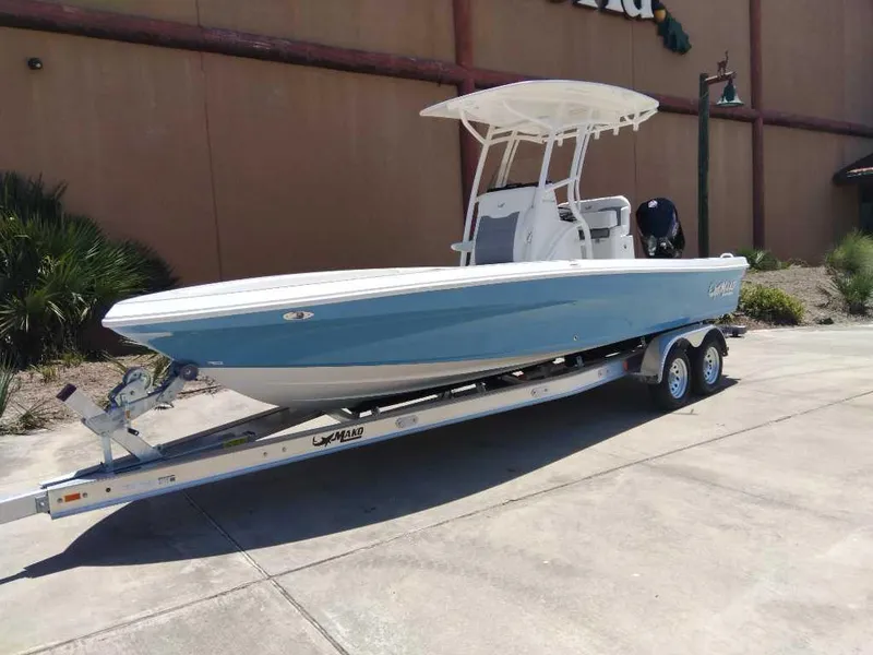 Slide: The Image of 2025 Mako 24 APEX boat on trailer, blue hull, parked outdoors. - 1