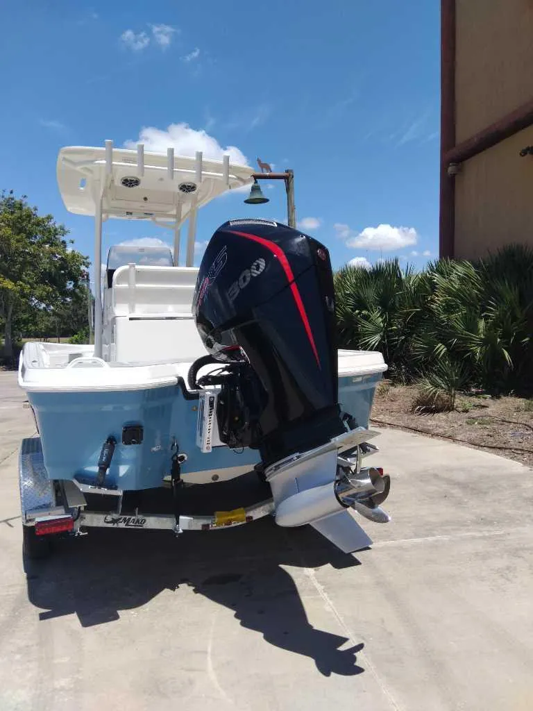 Slide: The Image of 2025 Mako 24 APEX boat with powerful outboard motor, parked outdoors under clear sky. - 6