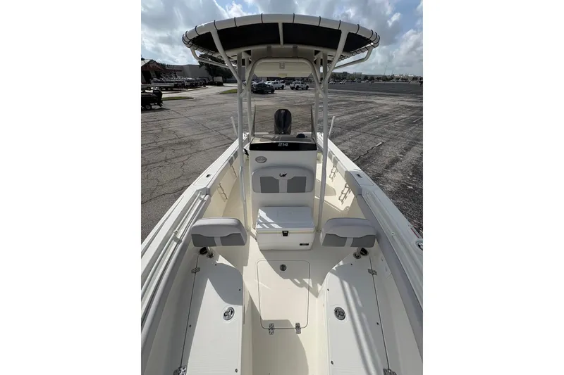 Slide: The Image of 2025 Mako 24 APEX boat interior with seating and console, parked outdoors under cloudy sky. - 7