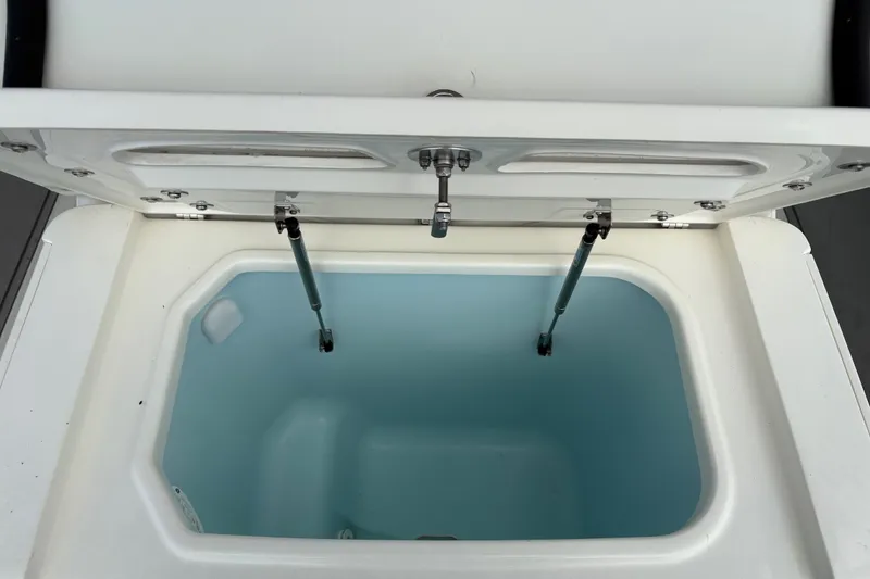 Slide: The Image of Open storage compartment on 2025 Mako 24 APEX boat, featuring hydraulic struts. - 10