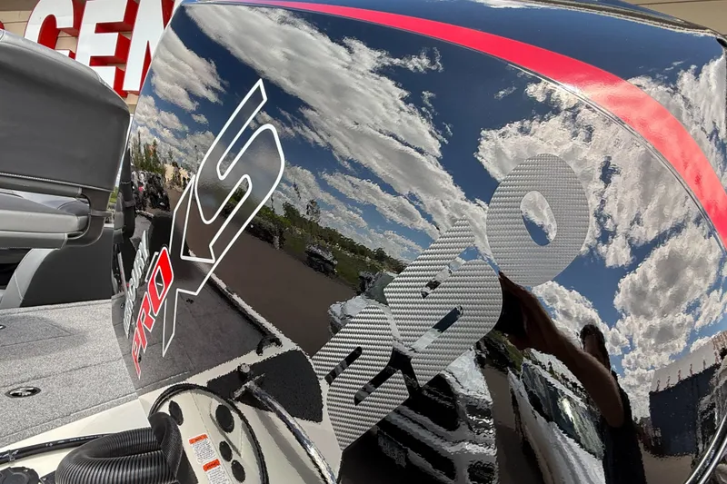 Slide: The Image of 2025 Tracker Savage 215 boat engine with reflective surface and sky reflection. - 8