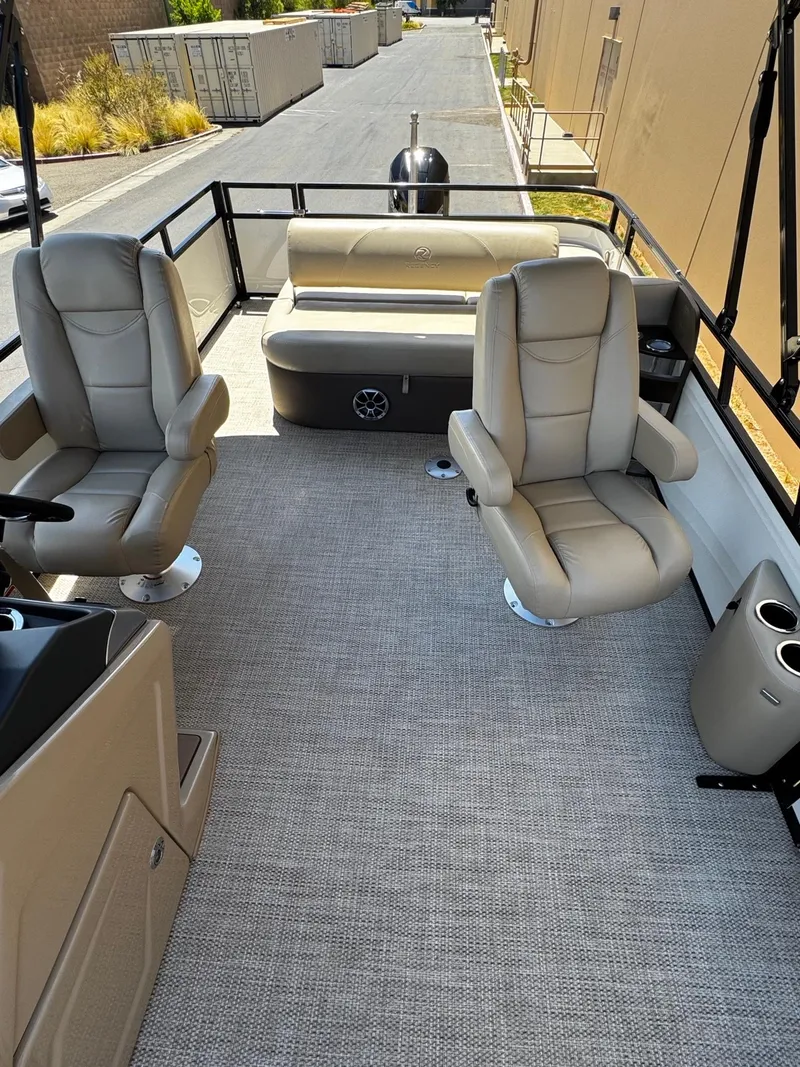 Slide: The Image of 2025 Regency 250 DL3 pontoon boat interior with beige seating and carpeted floor. - 2