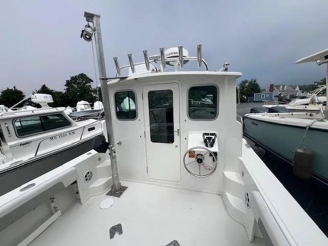 Slide: The Image of 2022 Parker 2520 XLD Sport Cabin boat, docked, showcasing rear cabin entrance and deck area. - 7