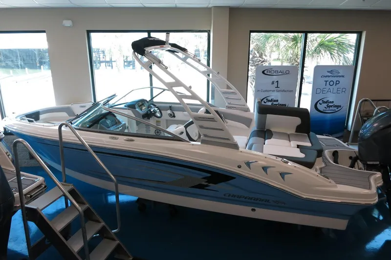 Slide: The Image of 2025 Chaparral 21 SSi Outboard boat displayed indoors at a dealership. - 36