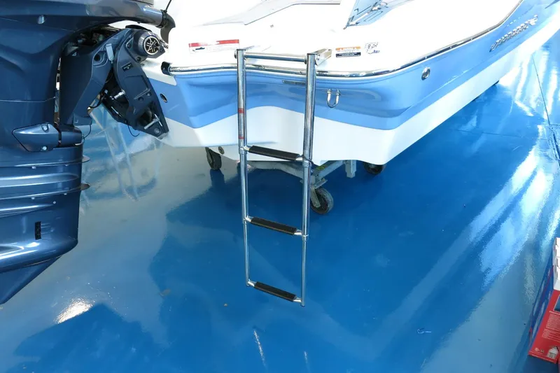Slide: The Image of 2025 Chaparral 21 SSi Outboard boat with ladder on blue showroom floor. - 43