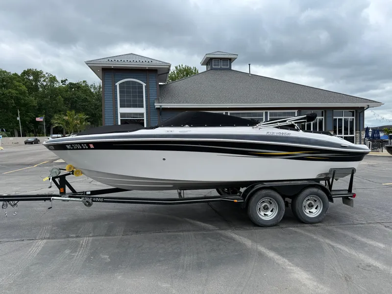 The Image of 2005 Four Winns Horizon 200 boat on trailer, parked near a building under cloudy skies. - 0