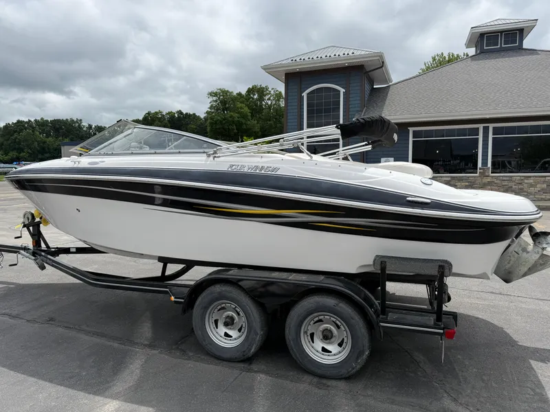 Slide: The Image of 2005 Four Winns Horizon 200 boat on trailer, parked near a building under cloudy skies. - 3