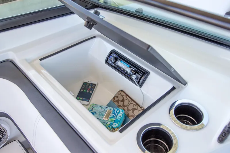 Slide: The Image of Manufacturer Provided Image: Storage compartment in 2016 Sea Ray SPX 210 boat with phone, wallet, and stereo system. - 17