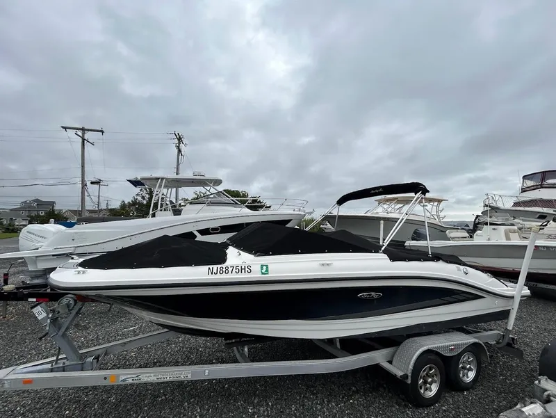 Slide: The Image of 2016 Sea Ray SPX 210 boat on trailer, covered, parked outdoors under cloudy sky. - 2
