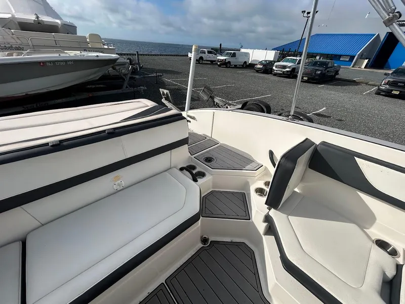 Slide: The Image of 2016 Sea Ray SPX 210 boat interior with white seating and gray flooring, docked near the ocean. - 6