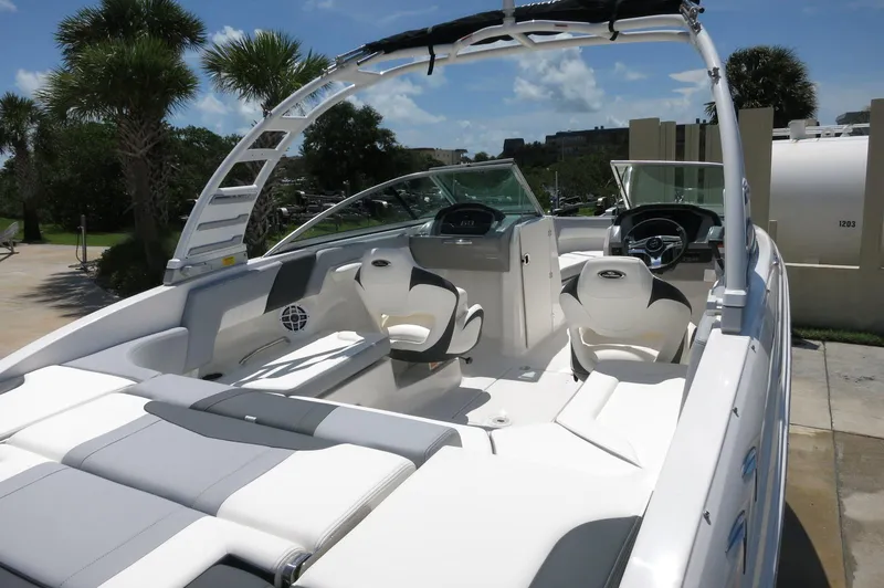 Slide: The Image of 2025 Chaparral 23 SSi OB boat interior with modern seating and dashboard, under sunny skies. - 14