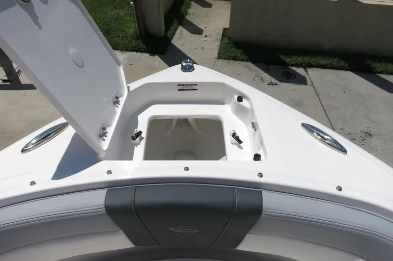 Slide: The Image of 2025 Chaparral 23 SSi OB boat bow storage compartment open, showcasing interior space. - 17
