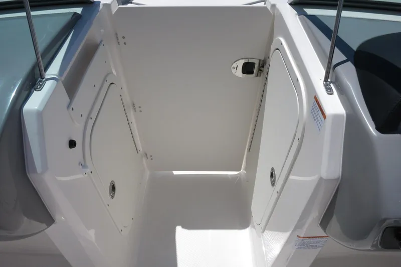 Slide: The Image of 2025 Chaparral 23 SSi OB boat storage compartment with white interior and secure latches. - 26