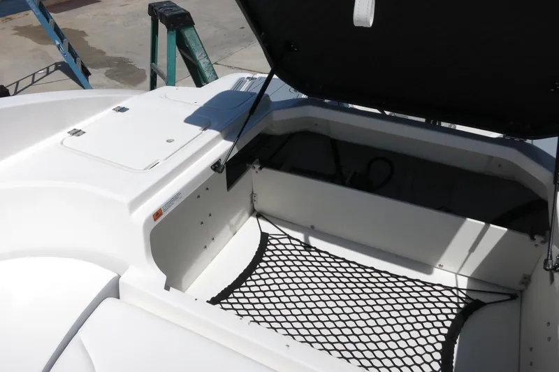 Slide: The Image of 2025 Chaparral 23 SSi OB boat storage compartment with open hatch and netting. - 32